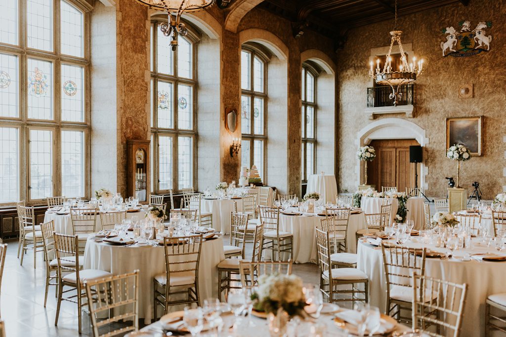 A grand, elegant banquet hall in Calgary with tall arched windows, chandeliers, and round tables set for a formal event—perfect for a photographer capturing a stunning wedding reception or special occasion.